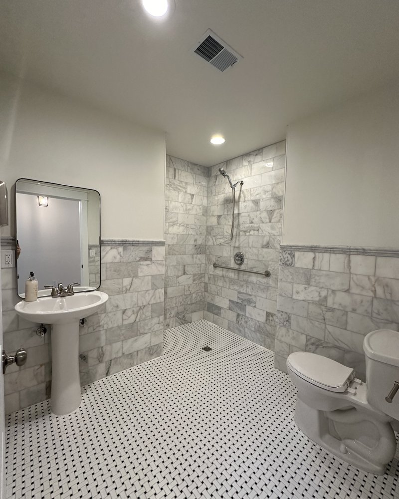 Accessible bathroom with walk-in shower, grab bars, and pedestal sink